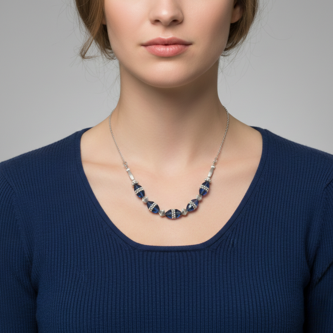 Woman wearing a blue beaded necklace against a gray background