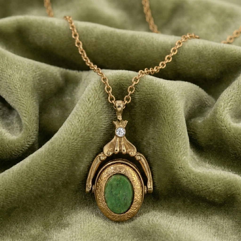 Gold necklace with a green gemstone locket pendant on a green fabric background