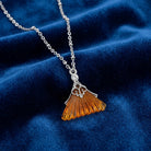 Silver necklace with a topaz pendant on a dark blue fabric surface 