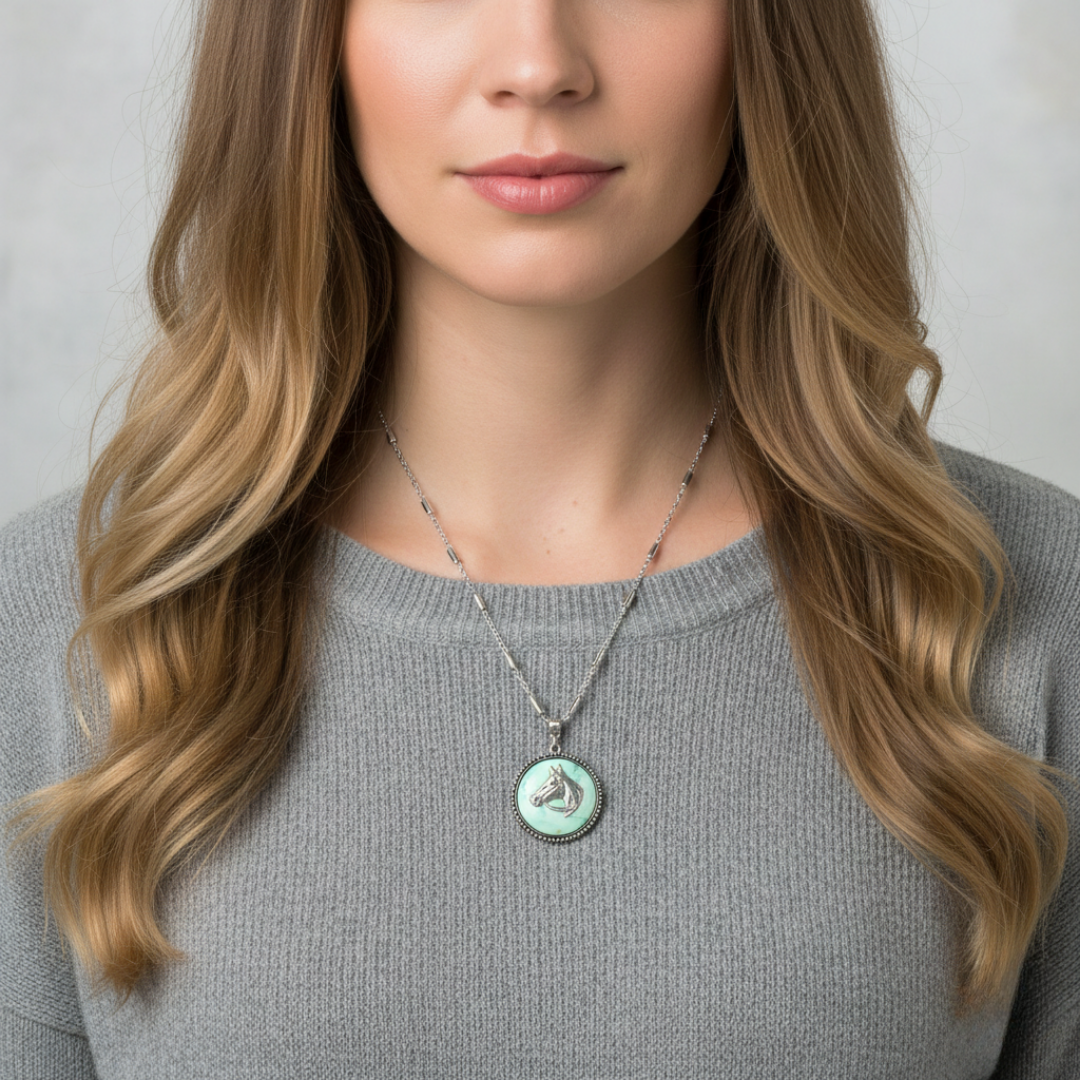 Woman wearing a necklace with a green and silver horse pendant against a neutral background