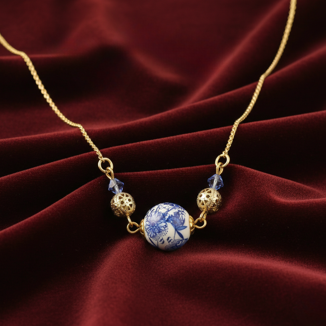 Necklace with blue and white bead and gold accents on a red fabric background