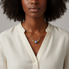 Woman wearing a gold necklace with a blue willow pendant against a neutral background