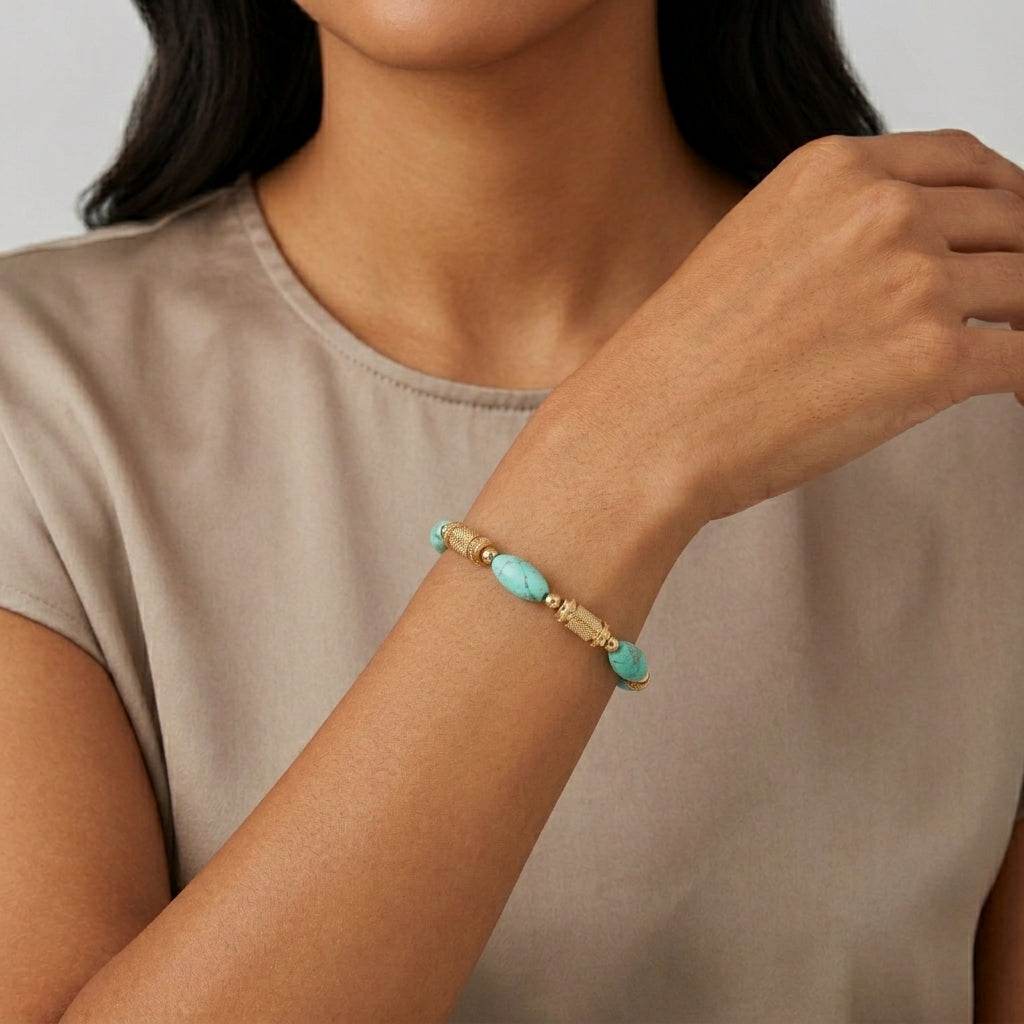 Woman wearing a gold bracelet with turquoise gemstones on a neutral background