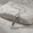 Oval Blue Stone Etched Whistle Pendant Necklace resting on stone