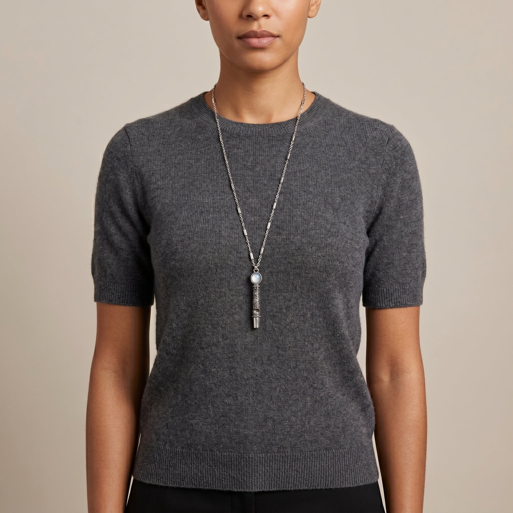 Person wearing a gray sweater with an Oval Blue Stone Etched Whistle Pendant Necklace