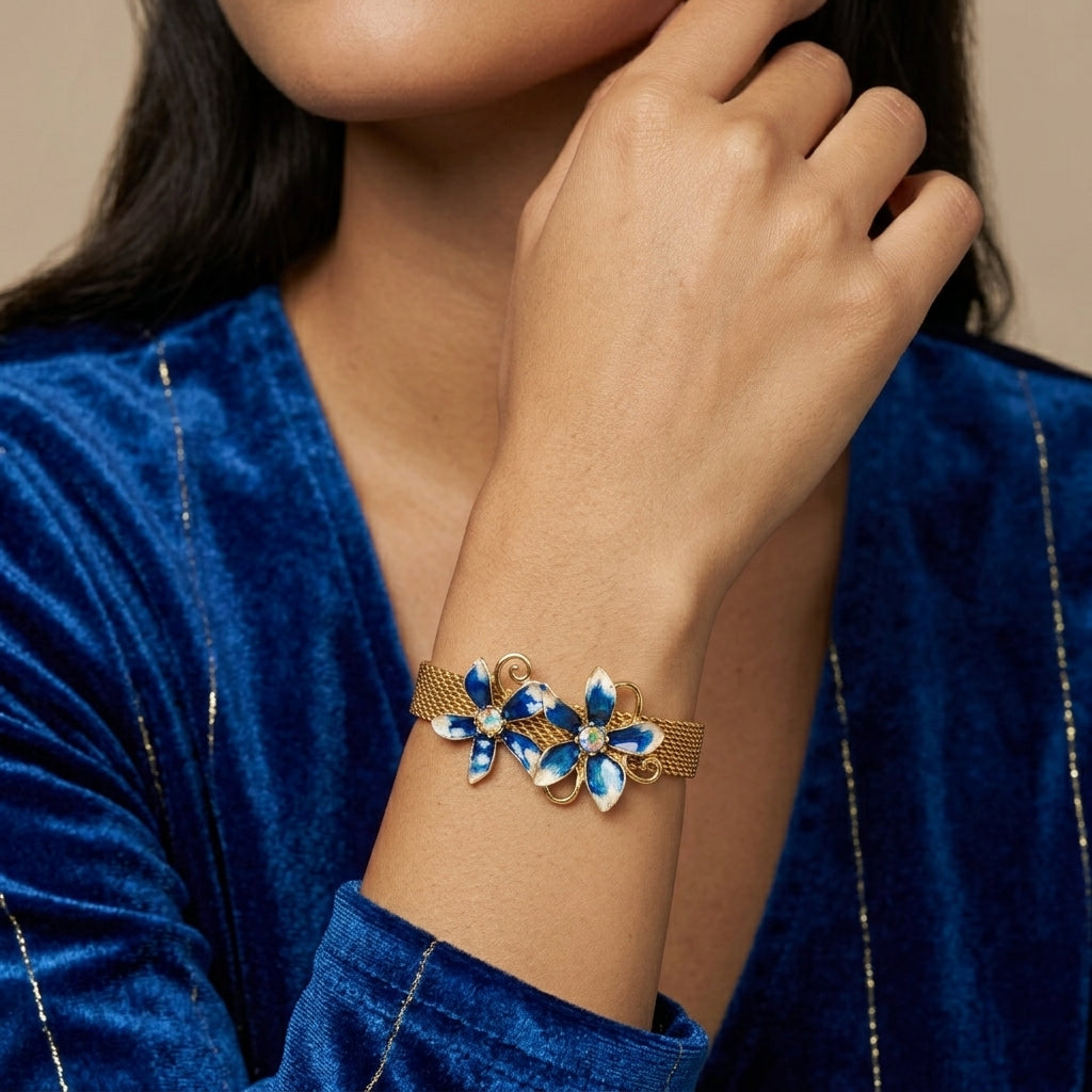 Woman wearing a gold bracelet with blue floral designs on a beige background