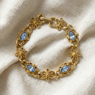 Gold bracelet with blue sapphire crystals on a beige fabric background