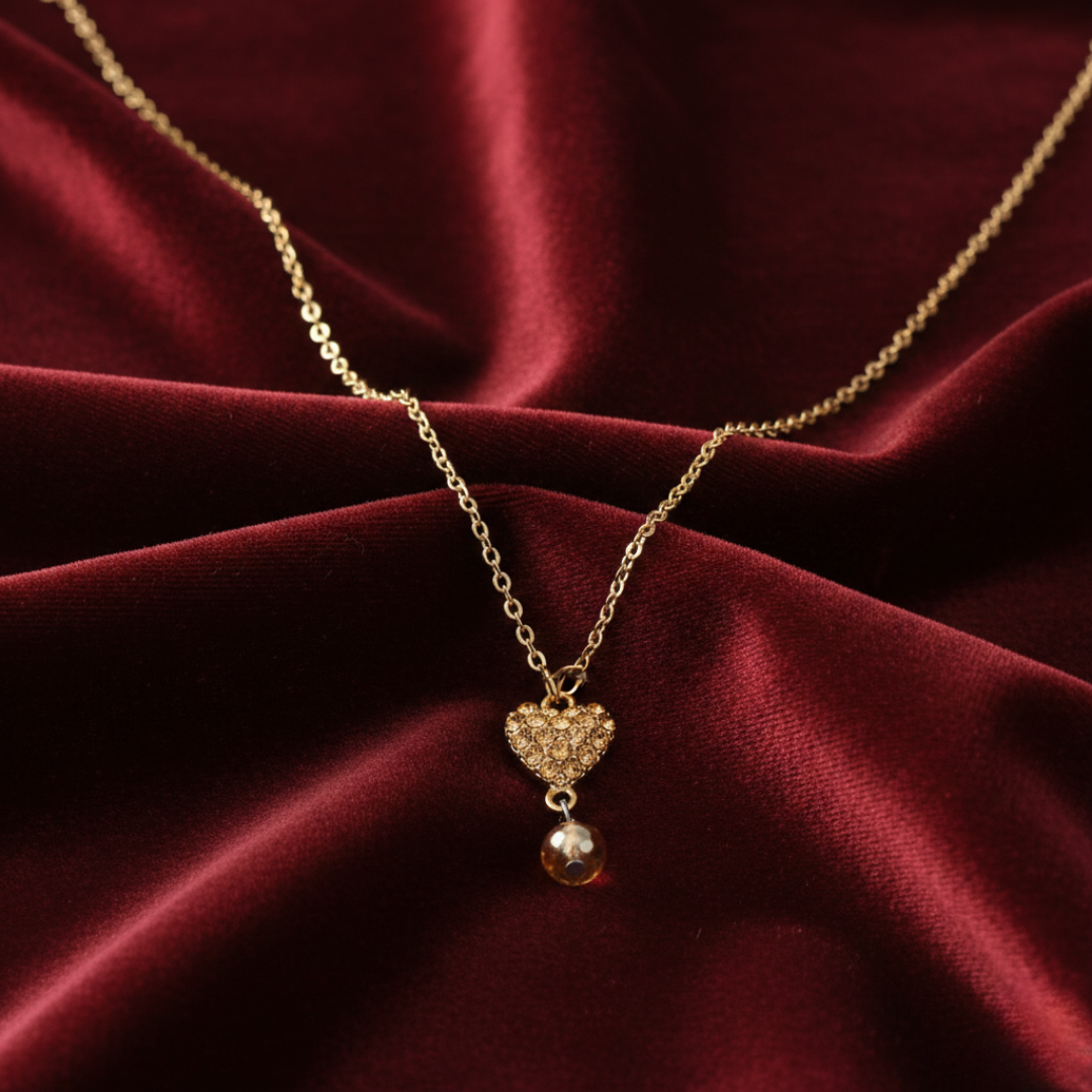Gold necklace with a heart-shaped pendant on a red fabric background