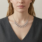 Woman wearing a silver necklace with clear crystals a neutral background