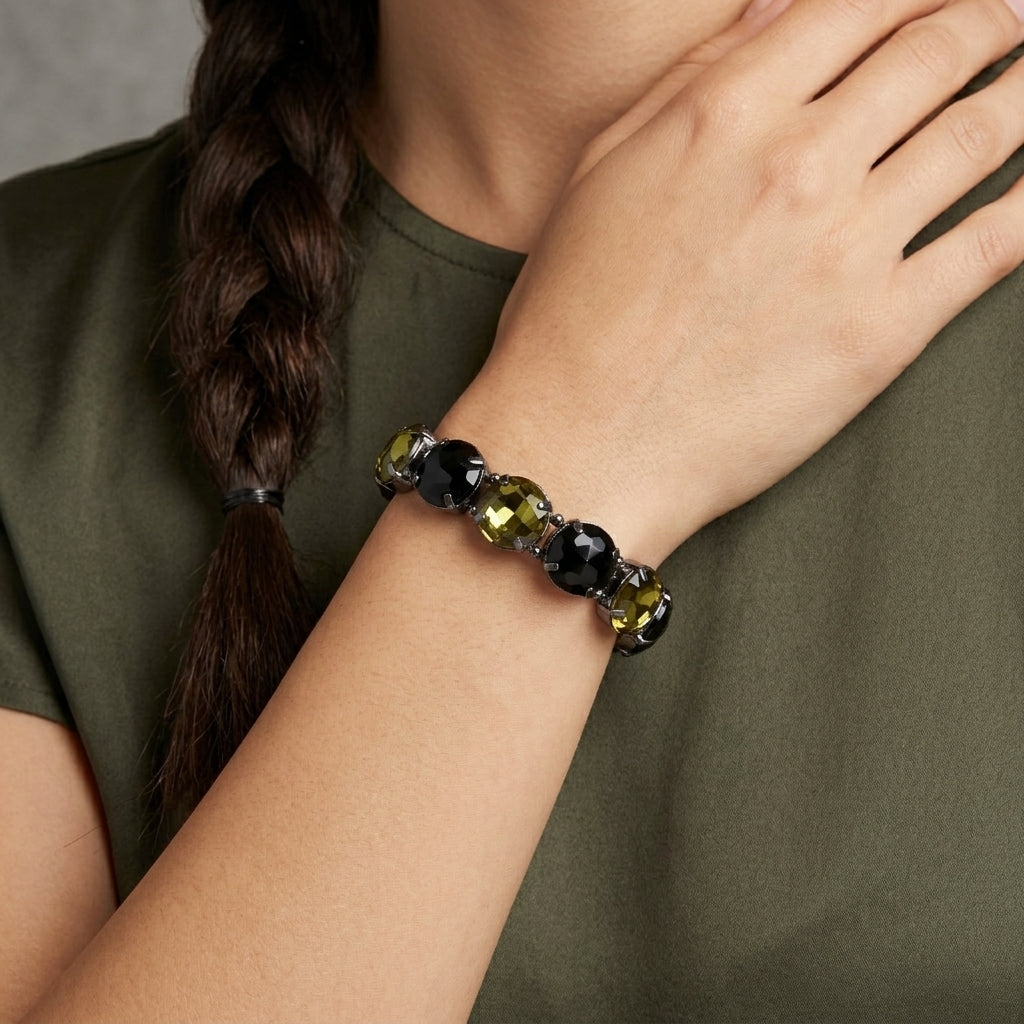 Person wearing a bracelet with black and green beads on an olive green shirt.