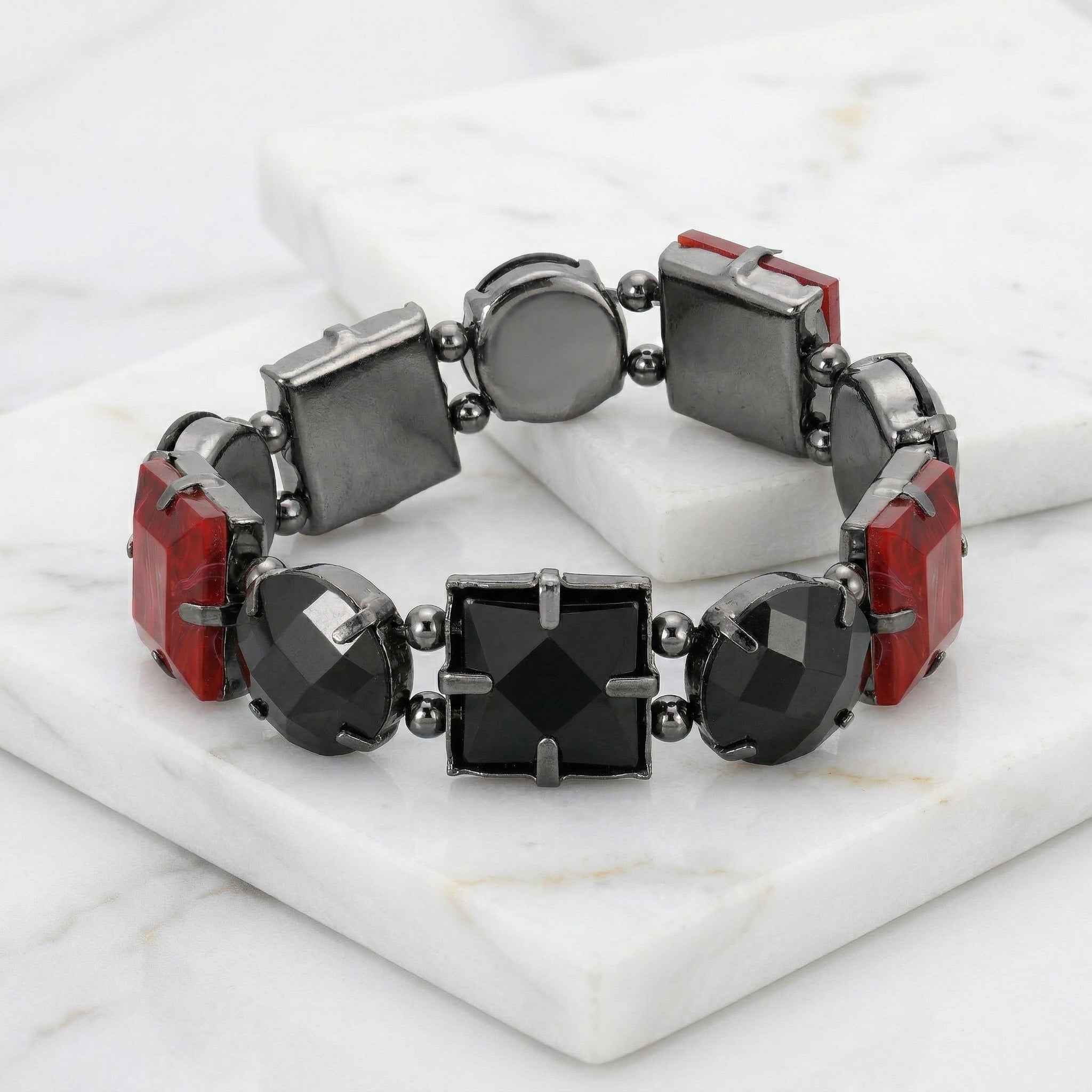 Bracelet with red and black square beads on a marble surface