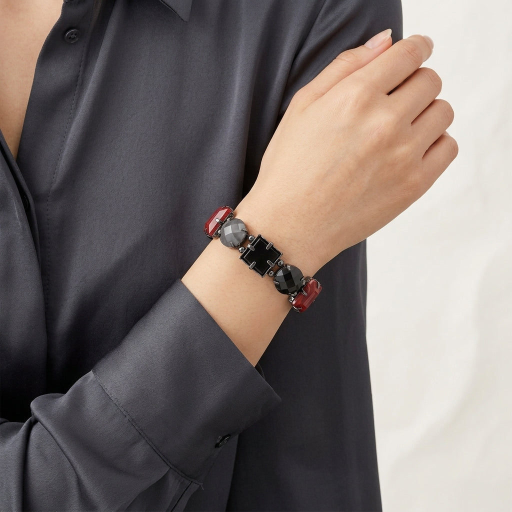 Person wearing a bracelet with red and black beads on a plain background