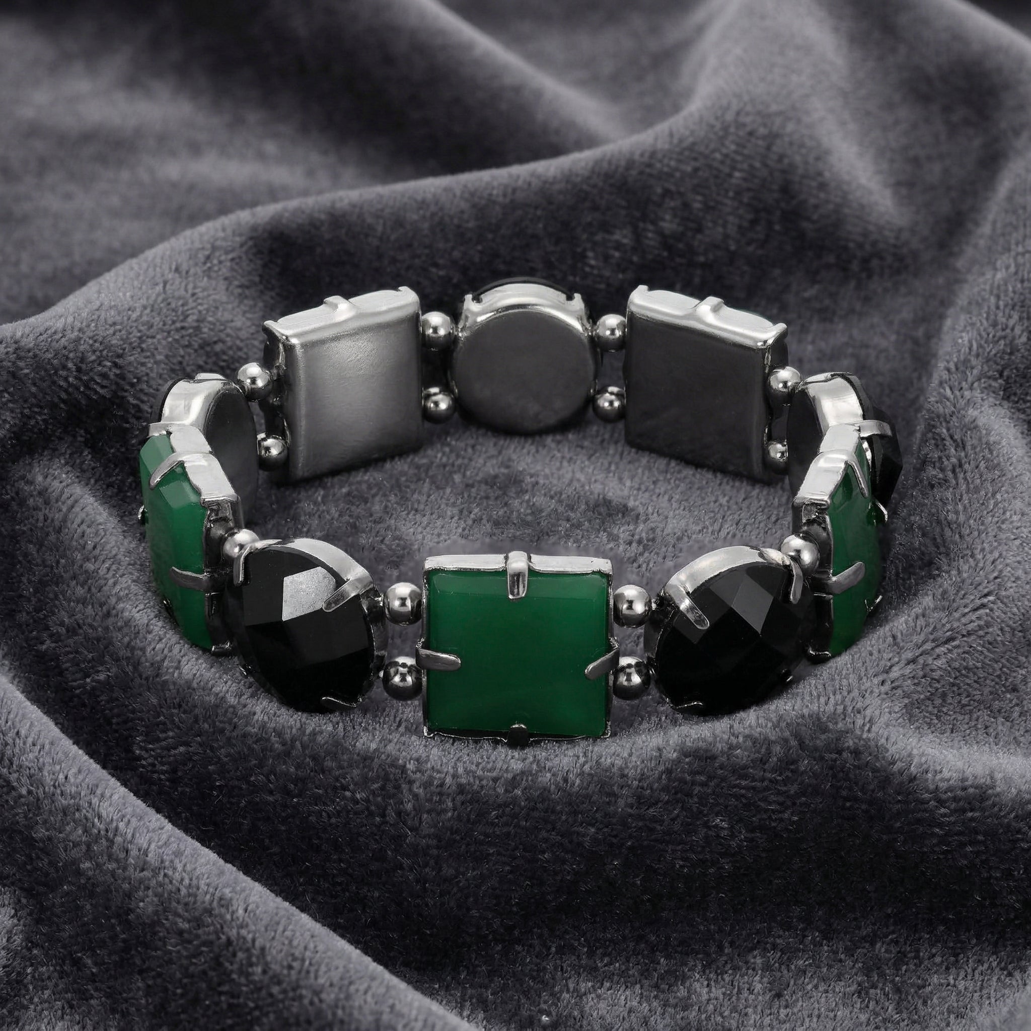 Bracelet with green and black stones on a dark fabric background