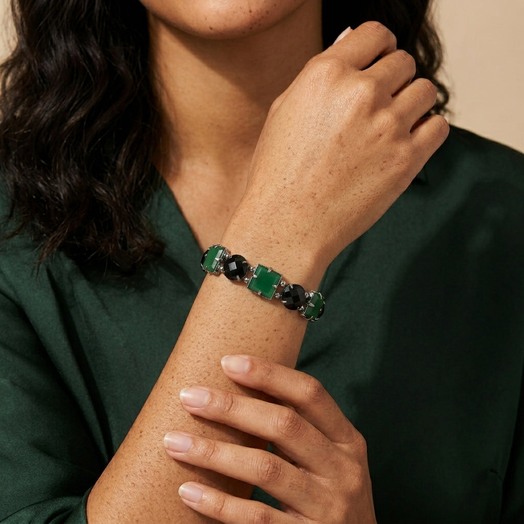Close-up of a person wearing a green and black beaded bracelet on a beige background