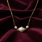 Faux pearl necklace with gold chain on a burgundy fabric background