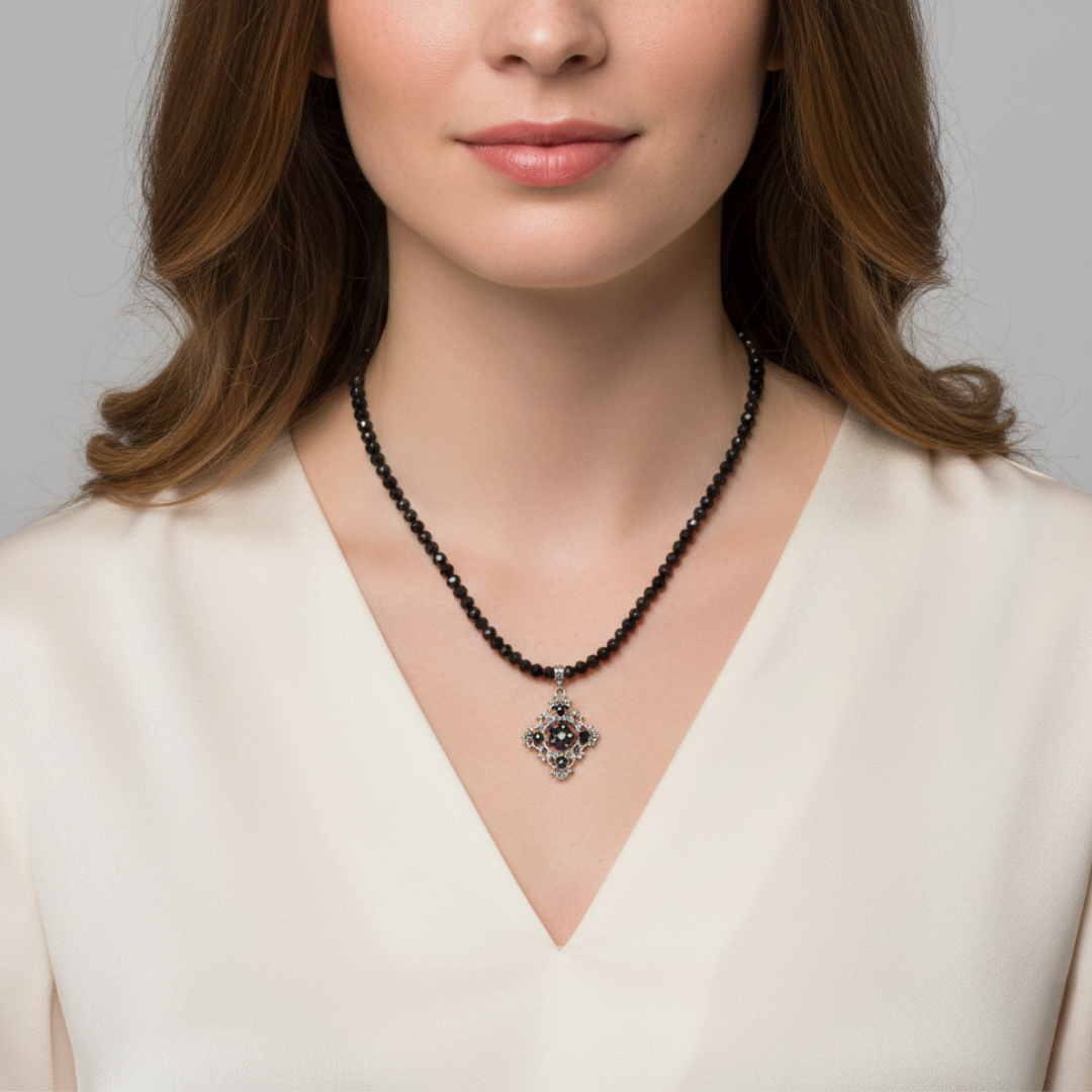 Woman wearing a black beaded necklace with a pendant against a neutral background