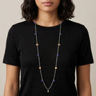 Person wearing a long Faceted Blue Bead & Gold Charms Link Necklace