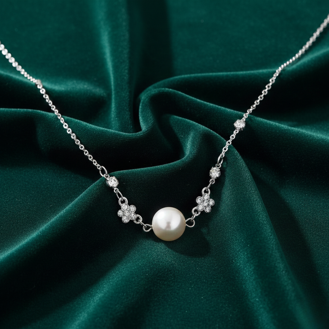 Pearl necklace with silver chain on a green fabric background