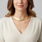 Woman wearing a gold necklace against a neutral background
