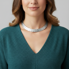 Woman wearing a silver necklace with a plain background