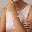 Person wearing a pink beaded bracelet on a neutral background