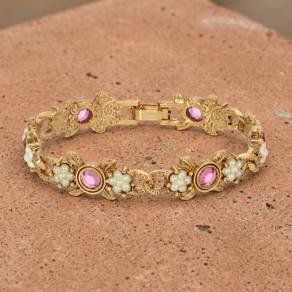 Gold bracelet with pink crystals and pearl-like elements on a textured surface