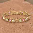 Gold bracelet with pink crystals and pearl-like elements on a textured surface