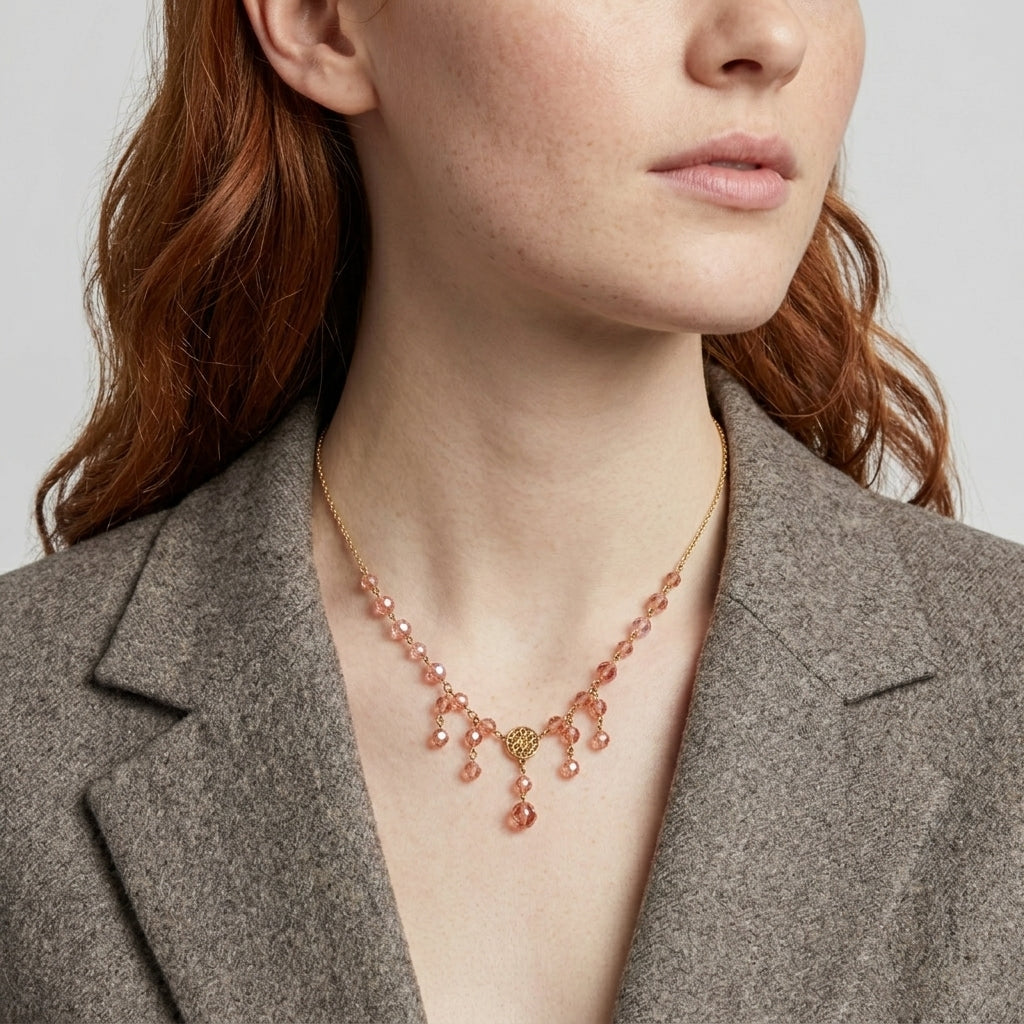 Woman wearing a delicate necklace with pink beads against a neutral background
