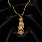 Gold cat-shaped spinner pendant with a pink gemstone on a black velvet background