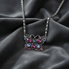 Butterfly-shaped necklace with colorful gemstones on a dark fabric background