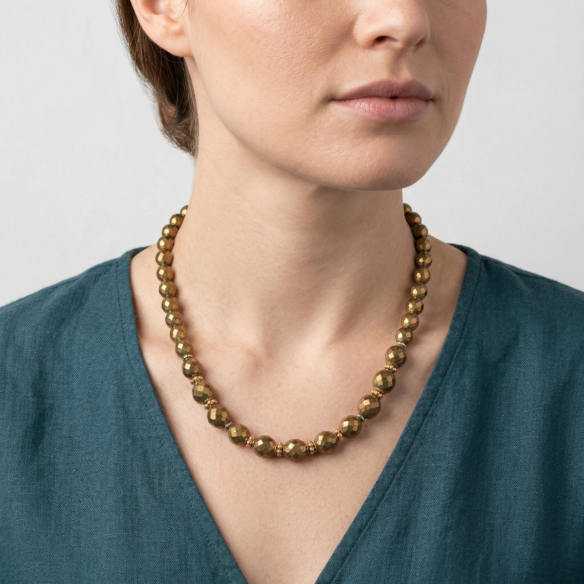 Woman wearing a bronze beaded necklace against a neutral background