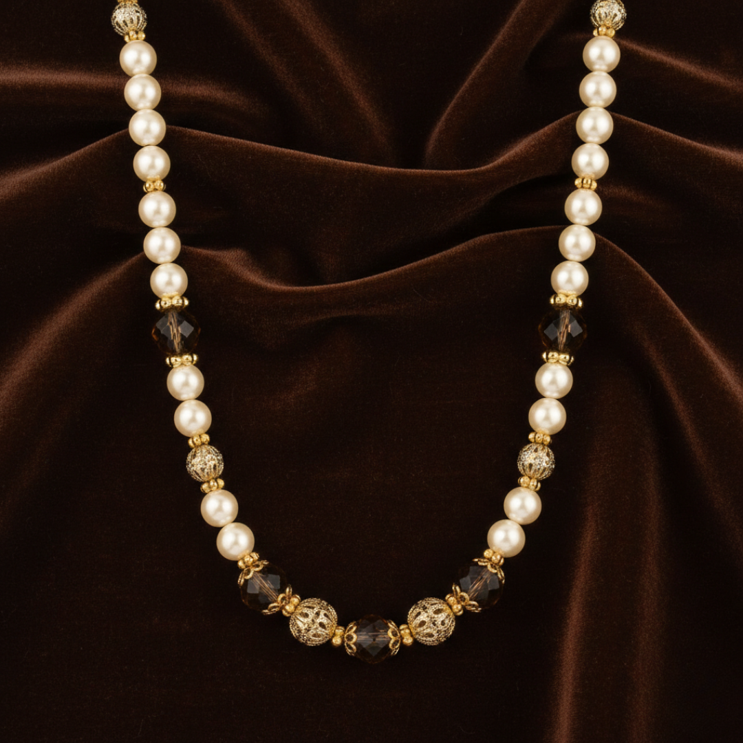 Pearl necklace with gold and black beads on a brown fabric background