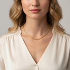 Woman wearing a gold necklace with a plain background