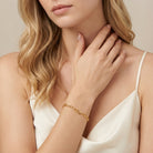 Woman in a white top wearing a skinny Gold Figaro Chain Bracelet