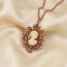 Yellow Topaz Crystal Carnelian Copper Cameo Floral Pendant Necklace resting on cream colored satin fabric