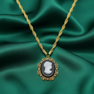 Gold necklace with a cameo pendant on green fabric