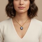 Woman wearing a gold necklace with a blue pendant against a beige background