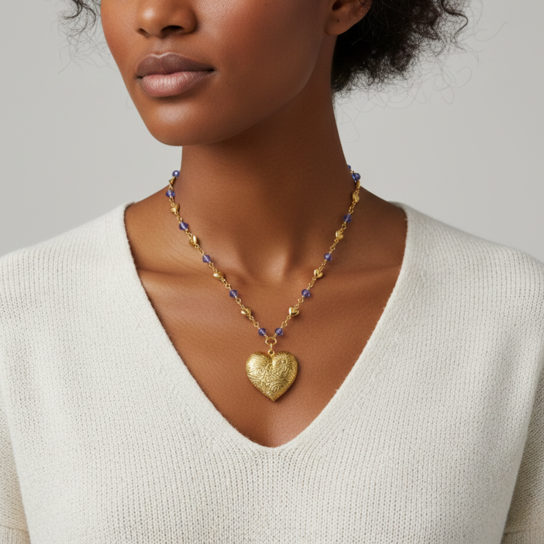Woman wearing a gold heart-shaped pendant necklace on a neutral background