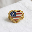 Heart-shaped American flag pin with gold border on a white background