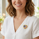 Woman wearing a white blouse with an American flag heart pin brooch.