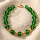 Green fire-polished beaded bracelet resting on linen fabric