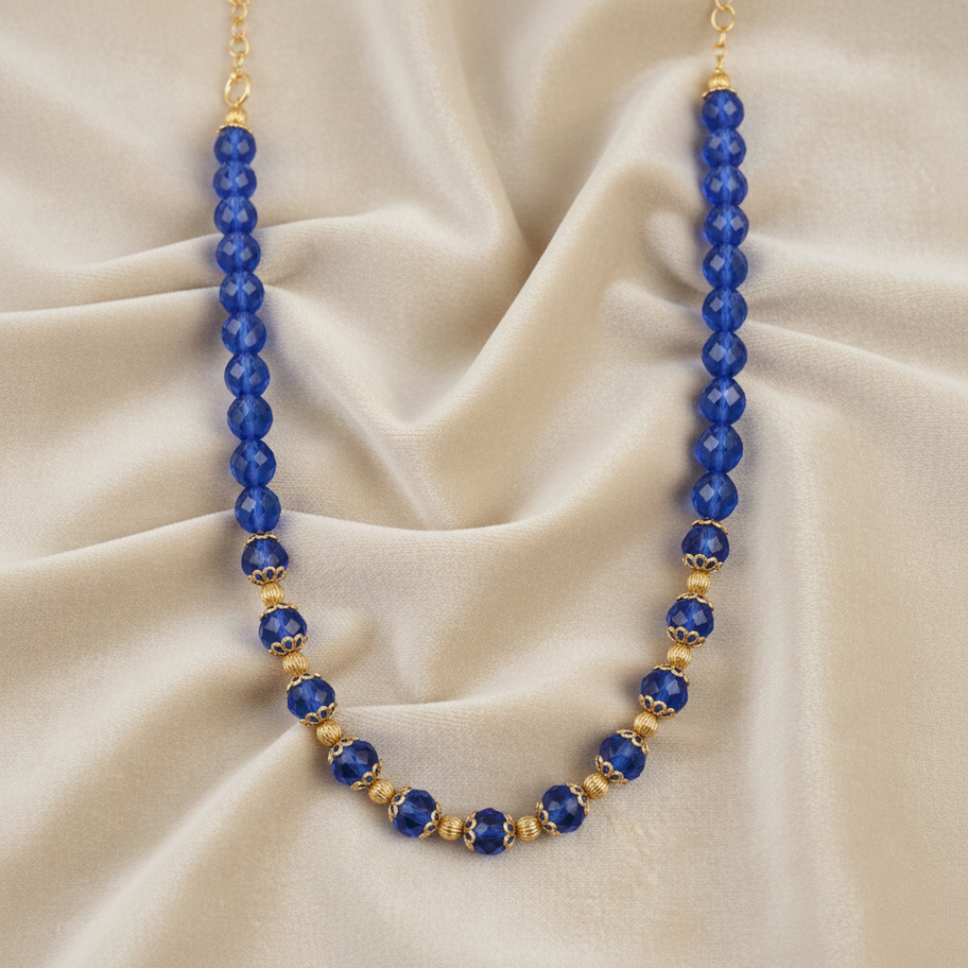 Necklace with blue beads and gold accents on a beige fabric background