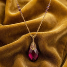 Briolette Purple Amethyst Glass Stone Pendant Necklace resting on mustard colored fabric 