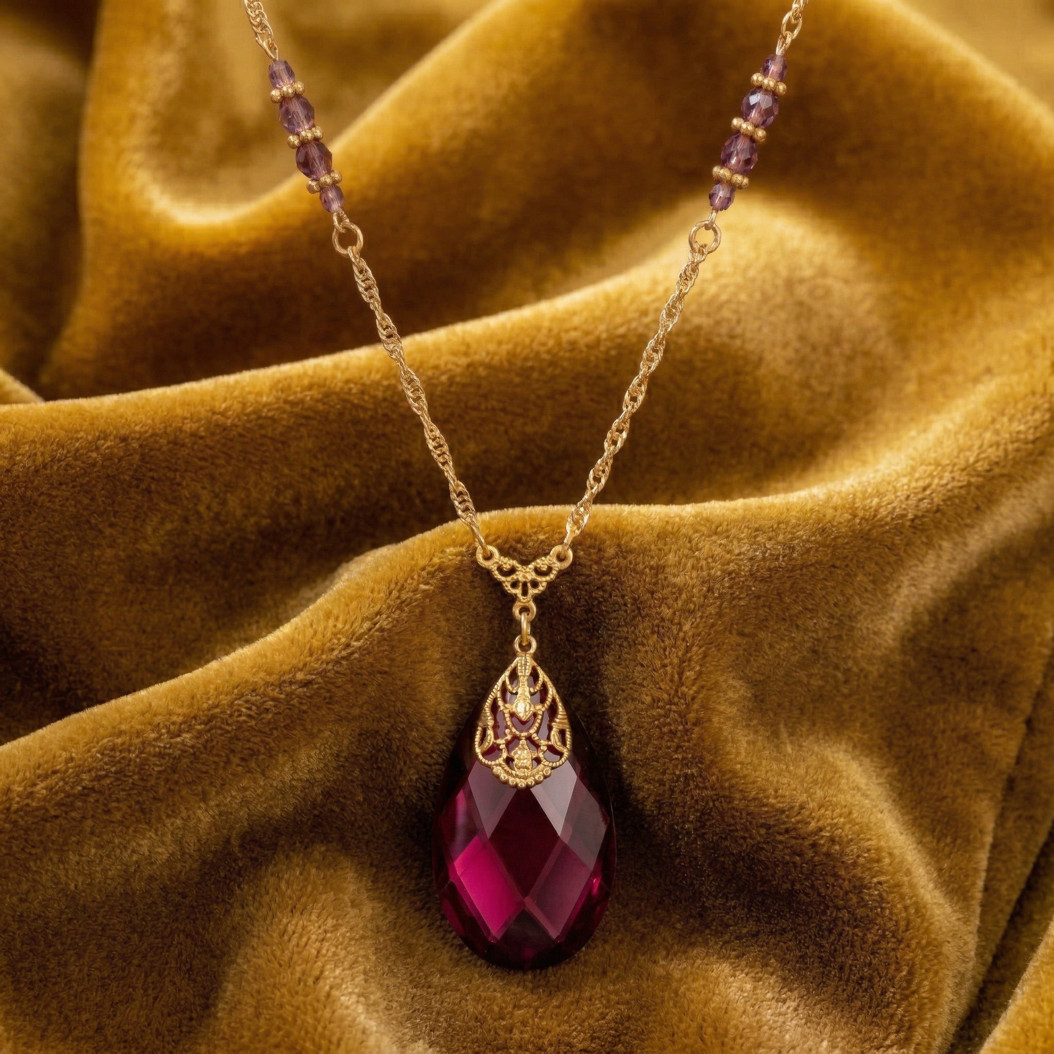 Briolette Purple Amethyst Glass Stone Pendant Necklace resting on mustard colored fabric 