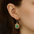 A close-up of a model's ear wearing a Green Octagon Moonstone & Gold Filigree Drop Earrings