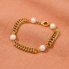 Gold tone link bracelet with white faux pearls resting on peach colored linen