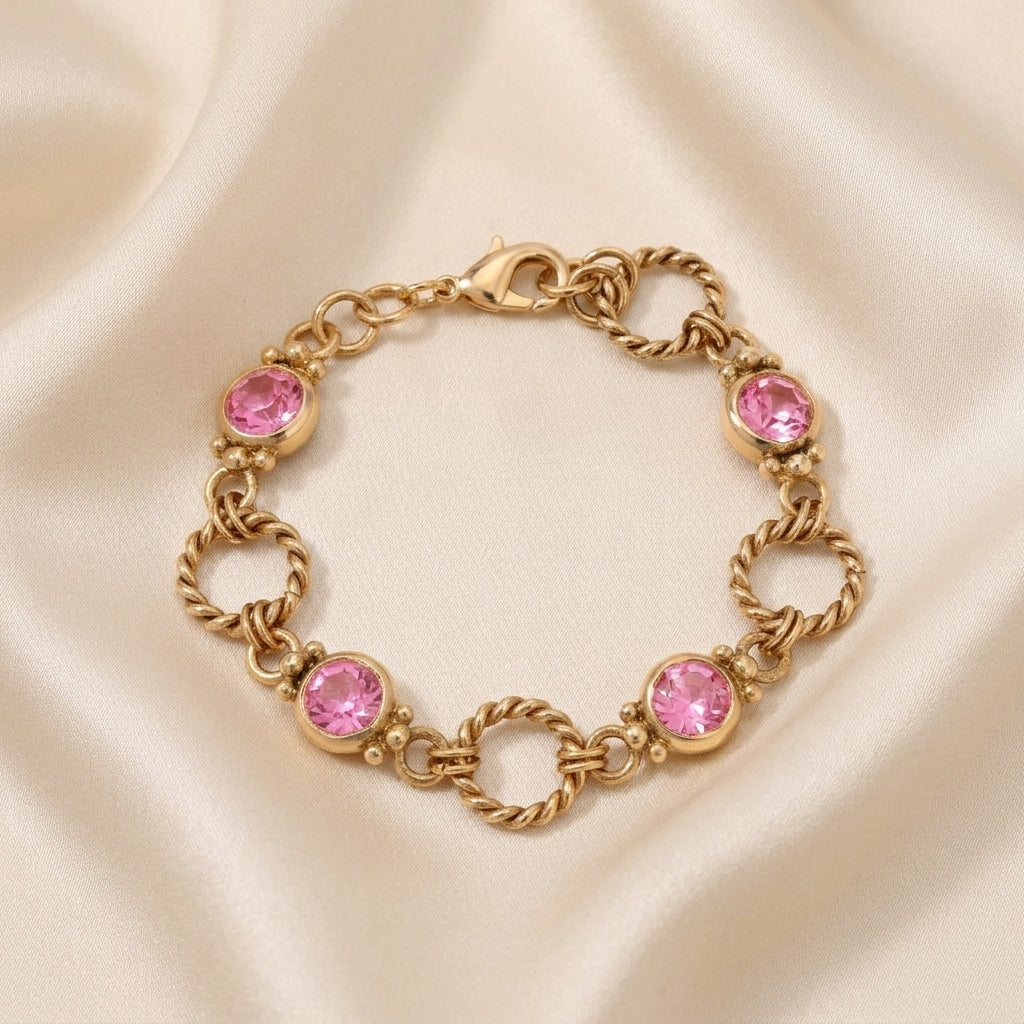 Gold tone twisted rope link bracelet with pink crystals