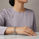 Woman wearing a silver tone twisted rope link bracelet with light sapphire blue crystals