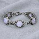Silver bracelet with purple cabochon stones on a light fabric background