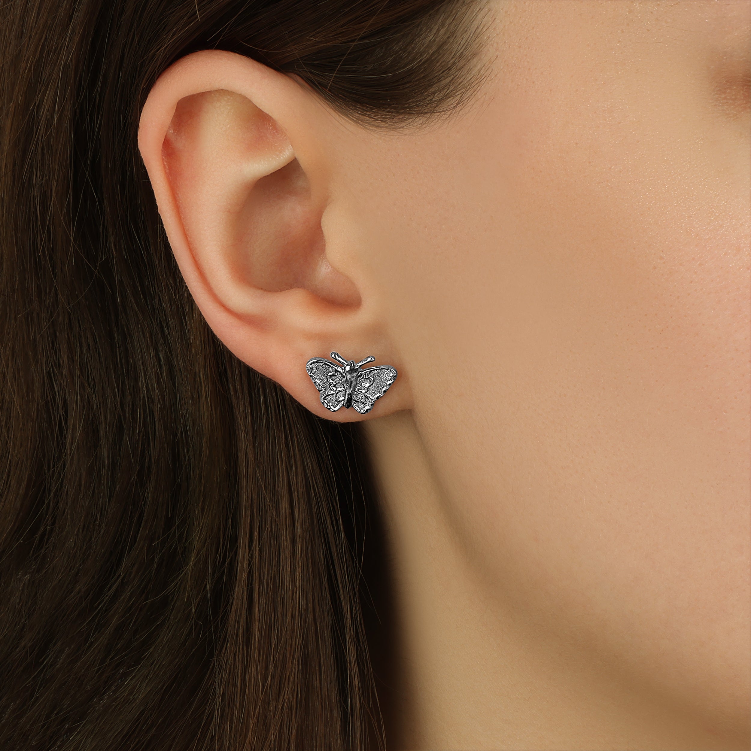 Close up of a woman wearing Dainty Silver Tone Butterfly Stud Earrings